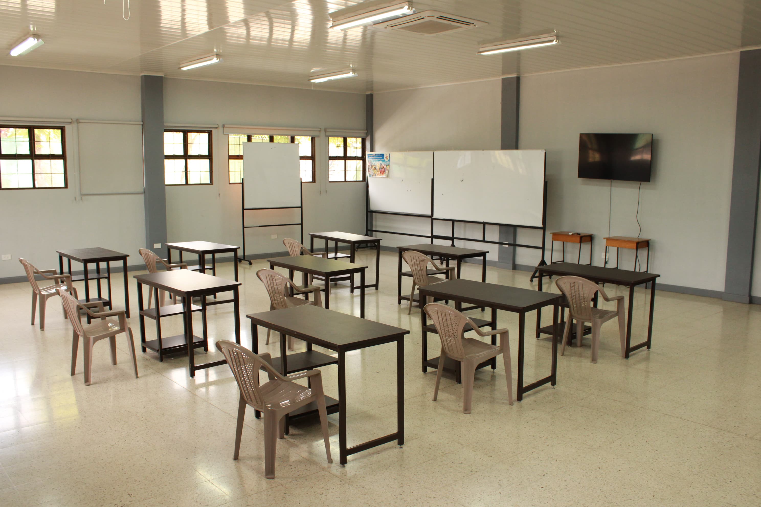 Ejemplo de montaje tipo aula con mesas, sillas, pizarras y pantalla en un salón del Centro Don Bosco