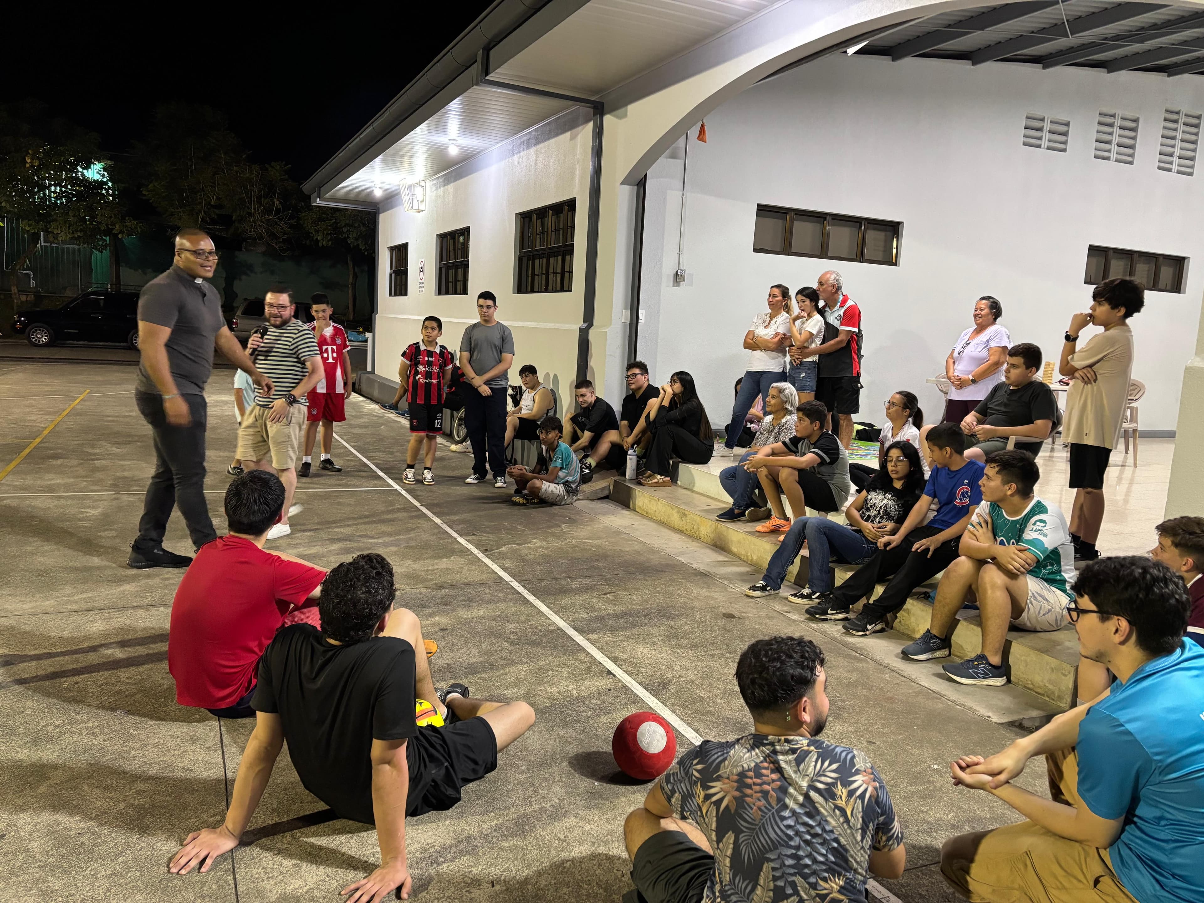 Participantes sentados y reunidos en el patio durante una actividad del Oratorio Nocturno.