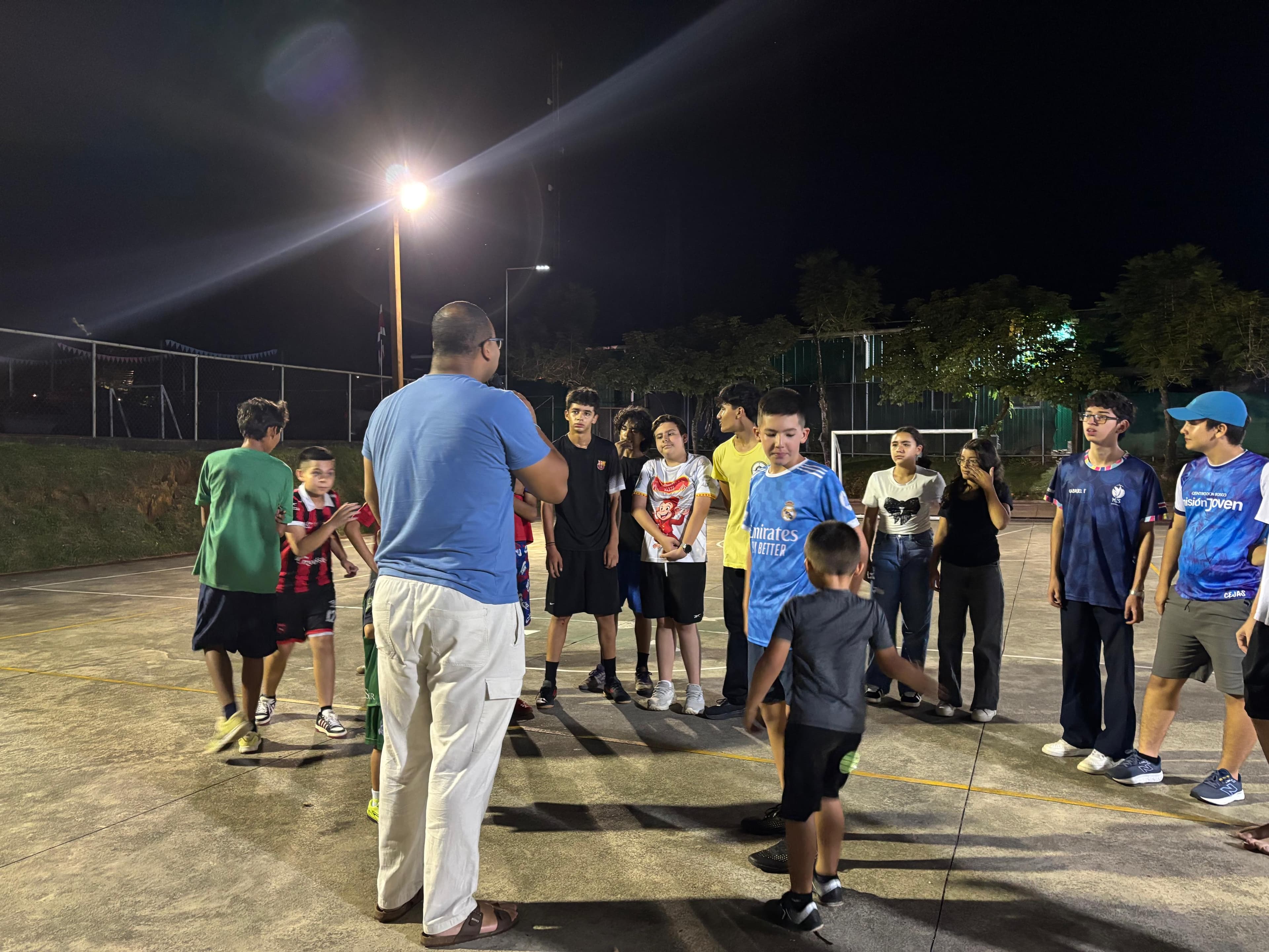 Jóvenes reunidos en la cancha durante una dinámica del Oratorio Nocturno.