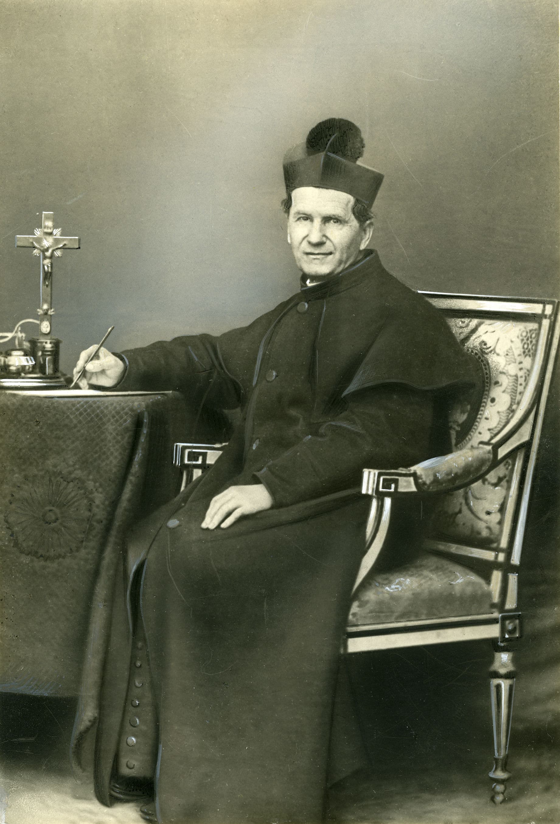 Retrato histórico de San Juan Bosco sentado junto a un escritorio.
